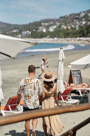 En la playa, playa de arena negra, camastros y sombrillas