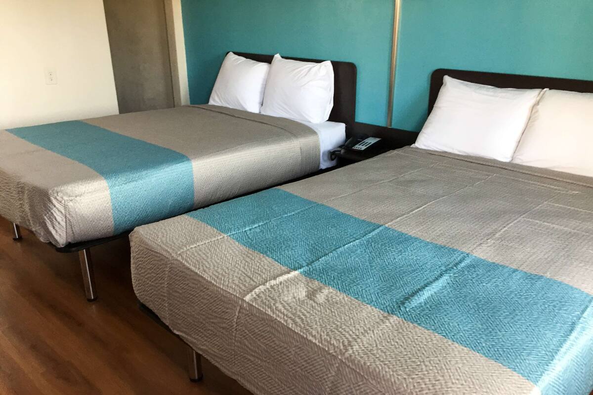 Dos camas individuales con colchas a juego, una mesita de noche y un enchufe de pared.