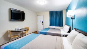 A hotel room with two beds, a desk with chairs, a flat-screen TV mounted on the wall, and a window with curtains. - Motel 6 Odessa, TX - 2nd Street (Odessa)