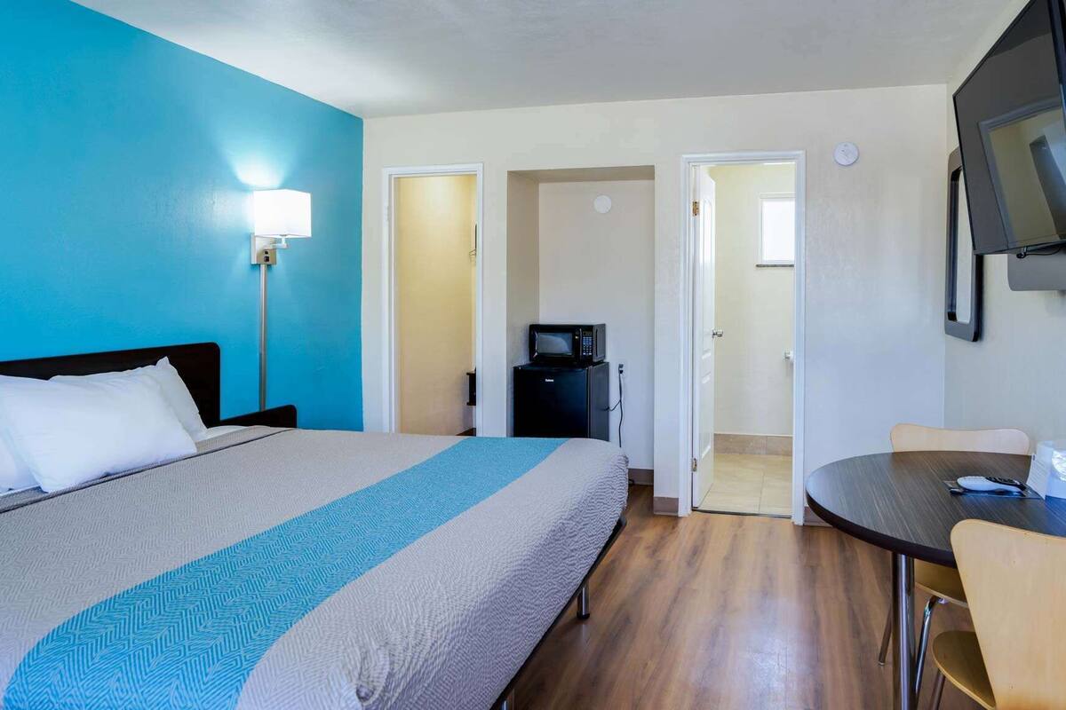 Habitación de hotel con cama, escritorio, silla, microondas y televisor.