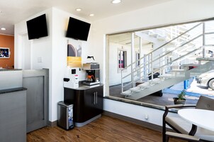 Habitación de hotel moderna con kitchenette, un amplio ventanal con vistas al exterior y una pequeña zona de estar.