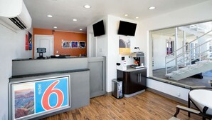 A modern hotel lobby with a reception desk, a coffee machine, and a staircase leading to an upper floor. - Motel 6 Odessa, TX - 2nd Street (Odessa)
