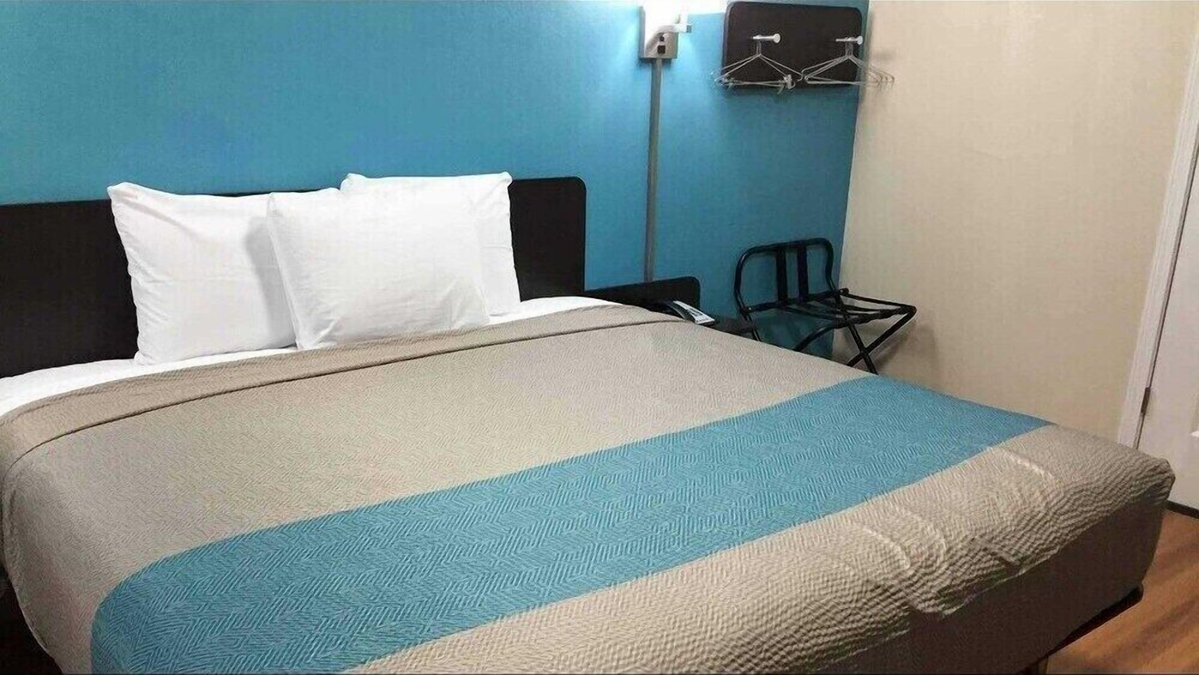 Ein Bett mit einem gemusterten Überwurf, einem schwarzen Kopfteil und weißen Kissen.