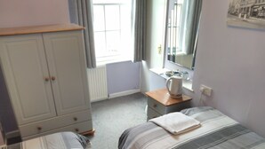 A bedroom with two beds, a wardrobe, a desk with a kettle, and a window with curtains. - The Bull (Birmingham)