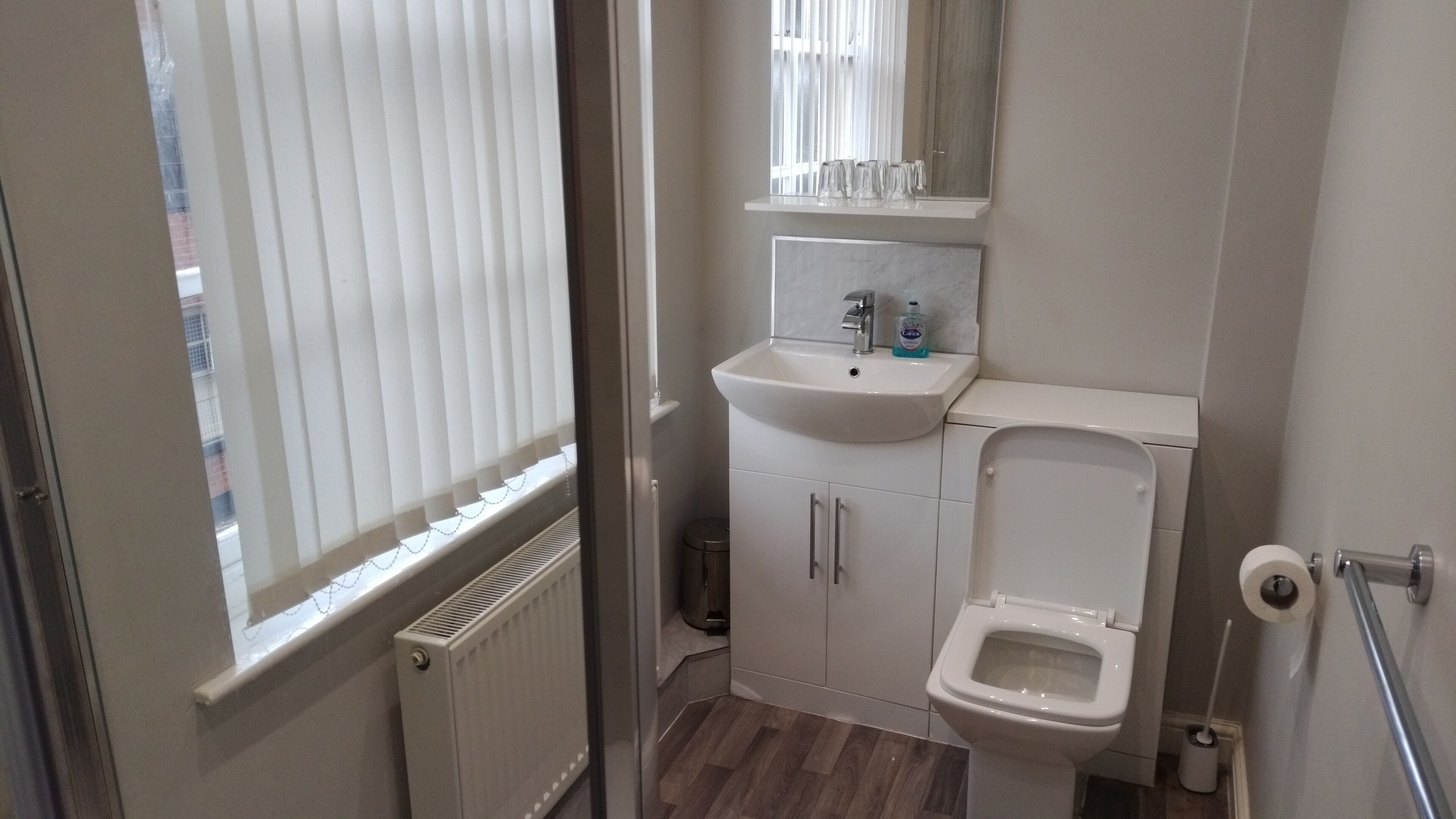 A small bathroom with a toilet, sink, and window.