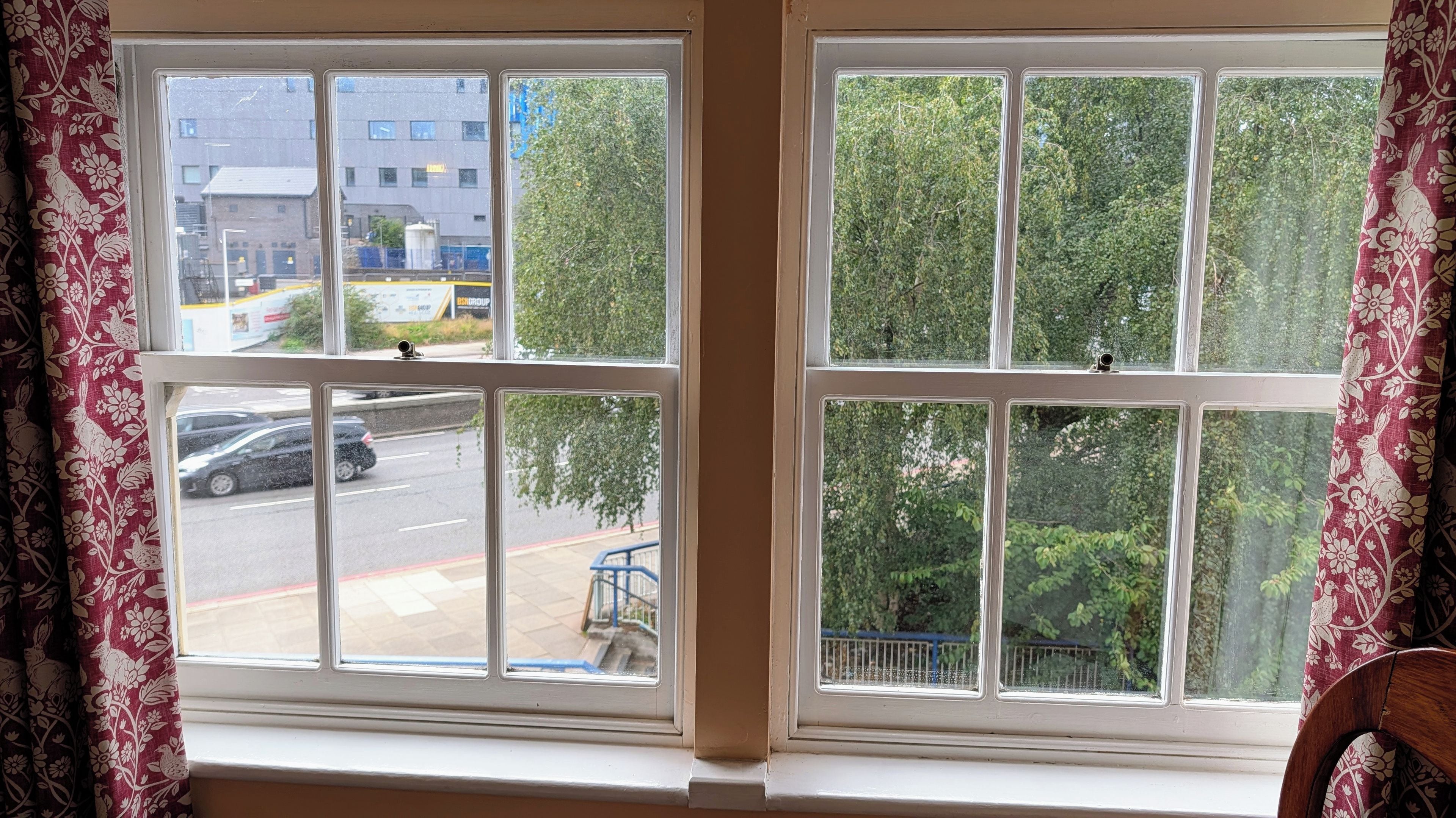 A window with multiple panes, a view of a street with cars, and a building with signage.