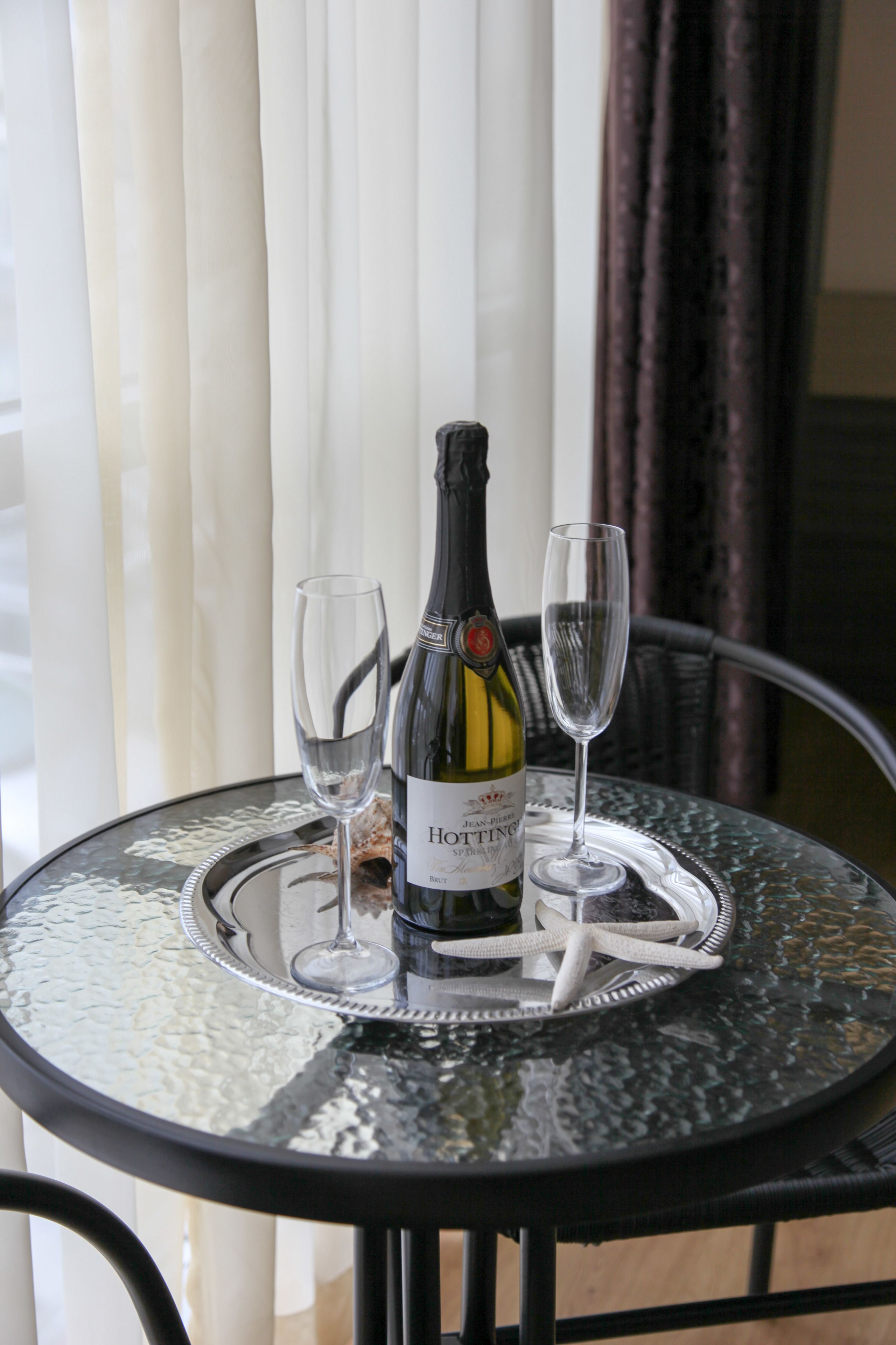 A bottle of Hotteling wine on a glass table with two wine glasses.