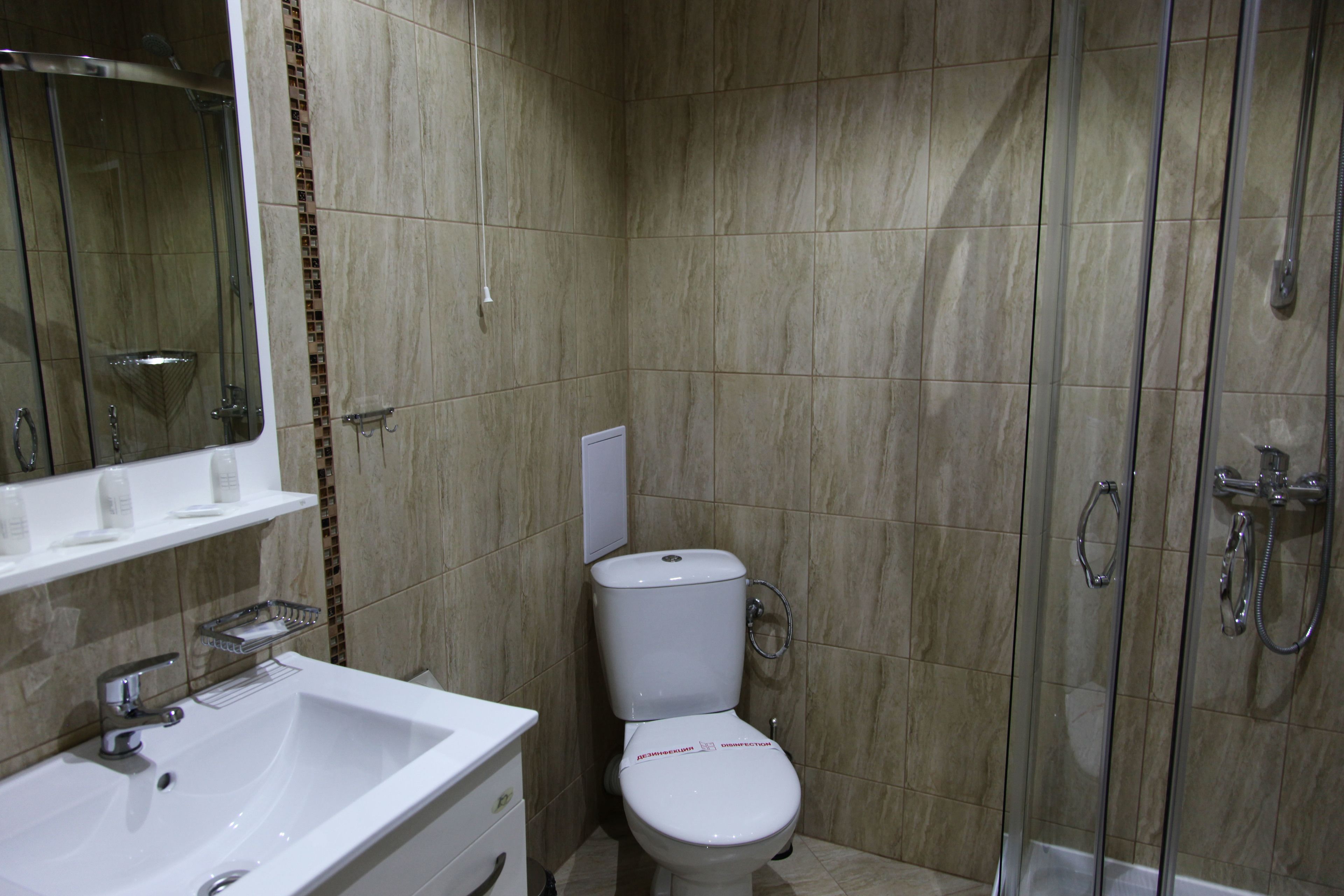 A bathroom with a white sink, toilet, and glass-enclosed shower.