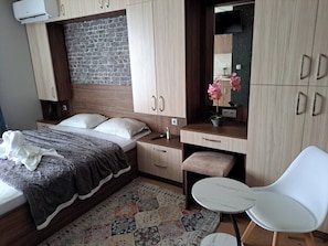 Quarto com cama, escrivaninha, cadeira, penteadeira e espelho.