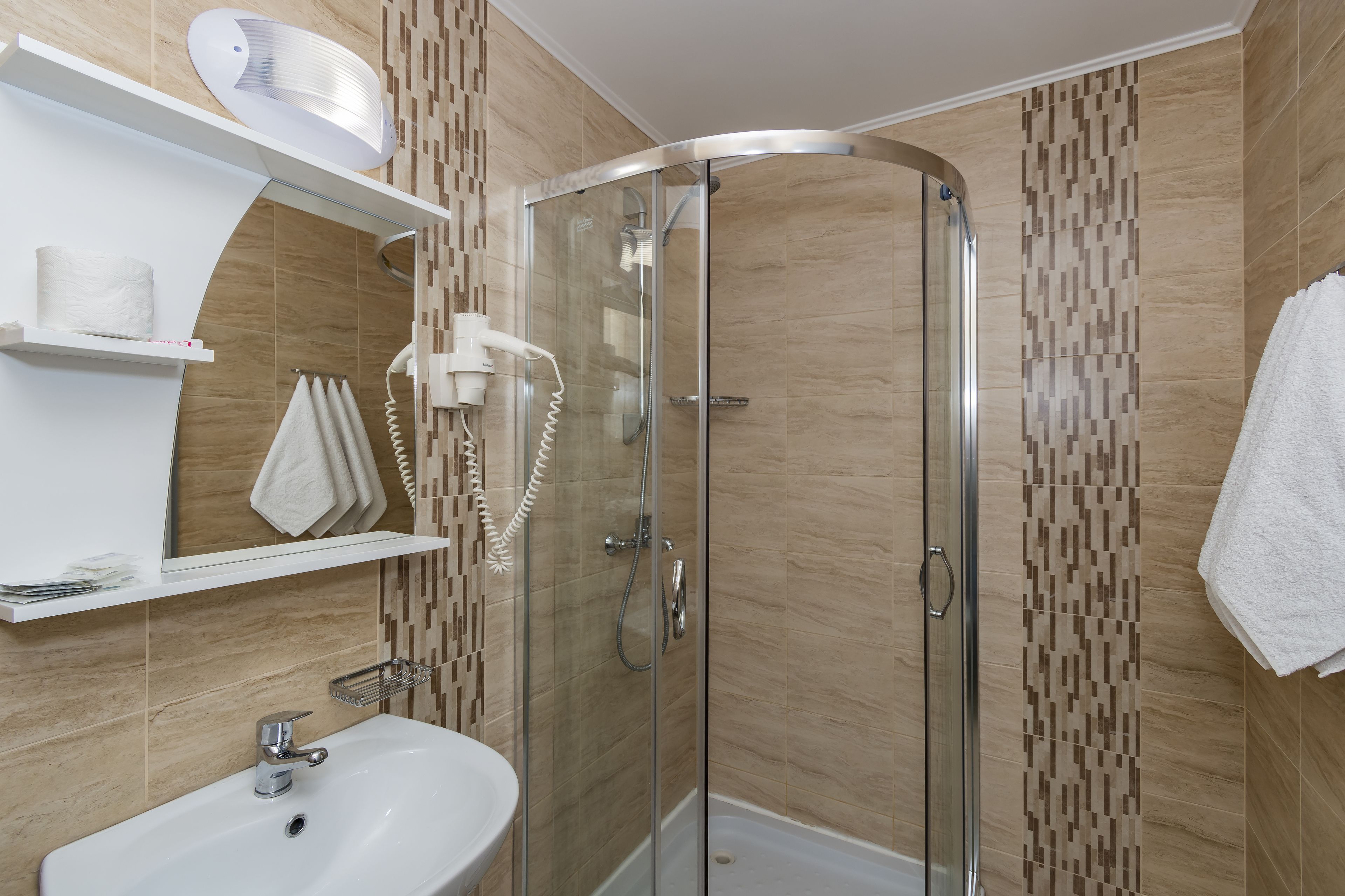 A modern bathroom with a glass-enclosed shower, a white sink, and a towel rack.