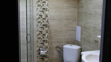 Un baño moderno con ducha de mampara de vidrio, inodoro y lavamanos.