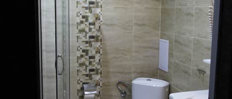 Un baño moderno con ducha de mampara de vidrio, inodoro y lavamanos.