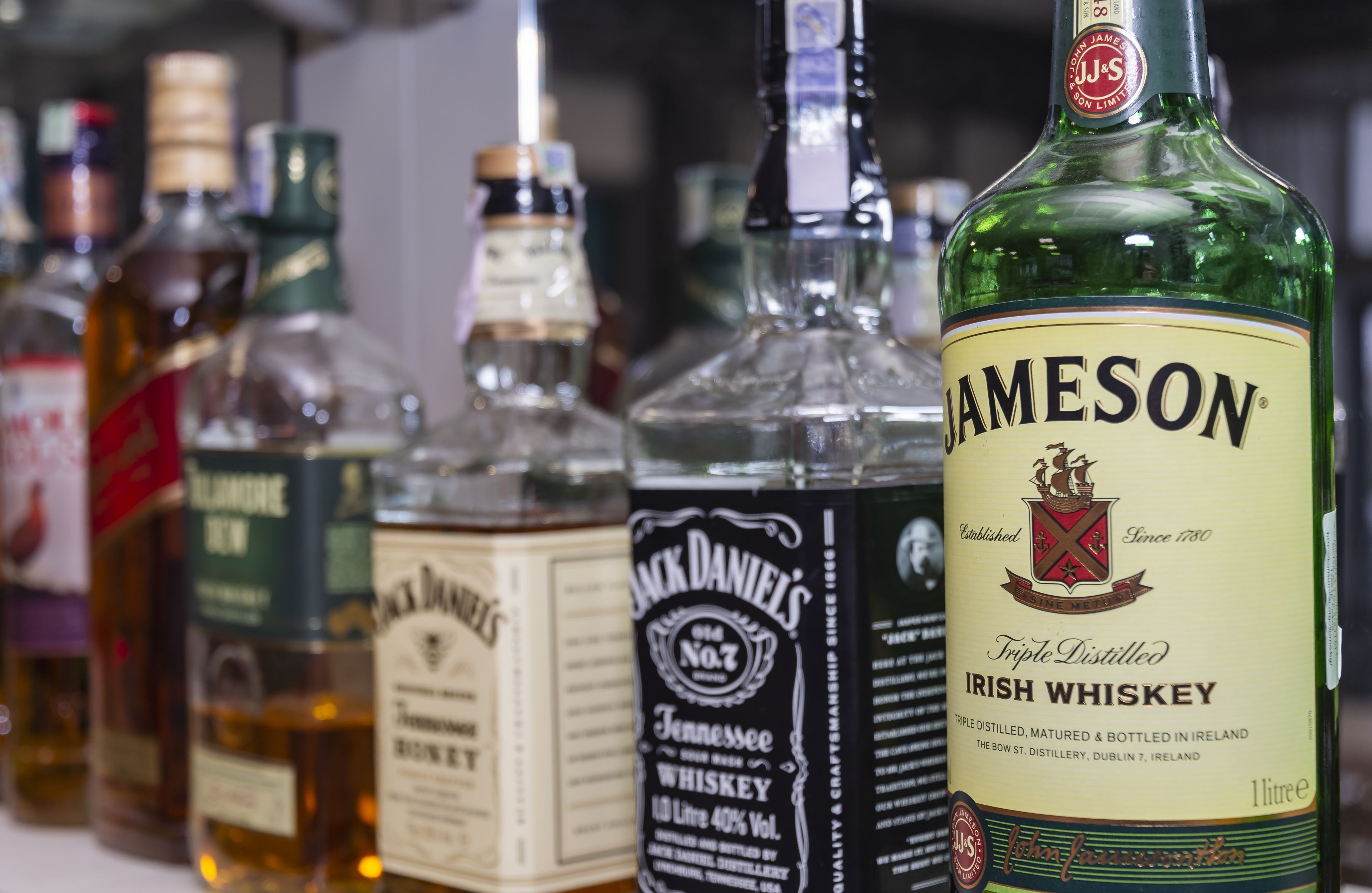 Variedad de botellas de whisky, incluyendo Jameson Irish Whiskey, sobre una estantería.