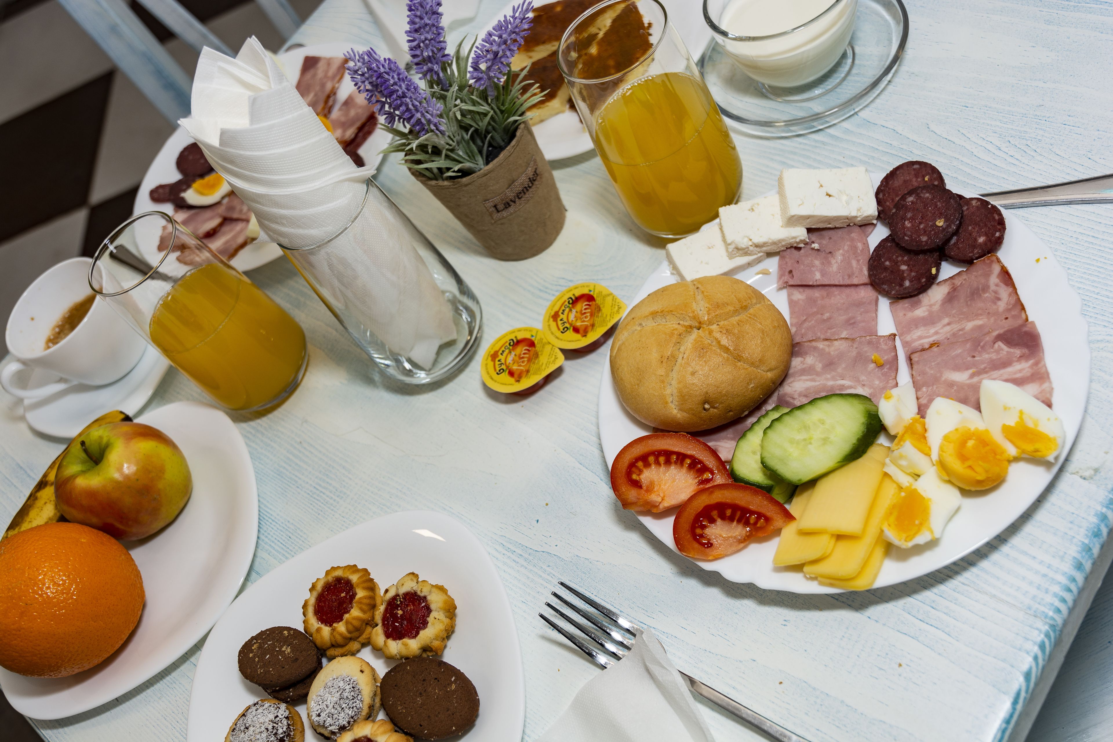 Una mesa de desayuno con diferentes alimentos, como huevos, queso, jamón y frutas.