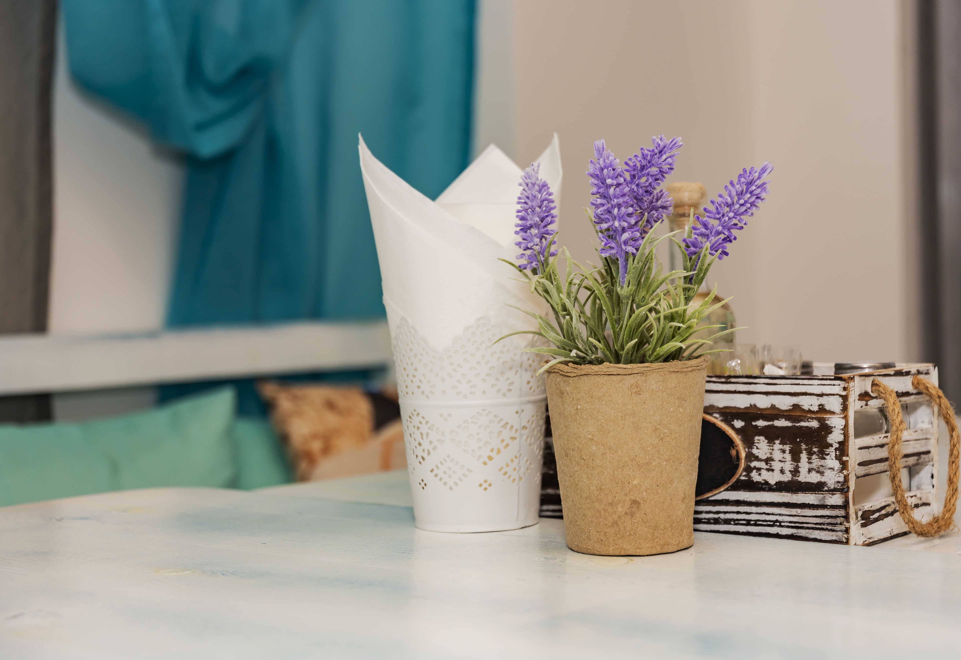 A table with a potted lavender plant, a white paper cone, and a rustic basket.