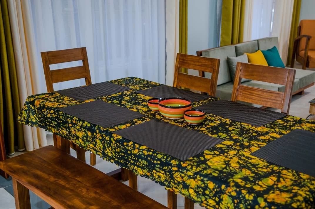 A dining area with a table set for four, surrounded by wooden chairs.