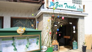 Un restaurant avec un panneau affichant le menu et une enseigne portant l’inscription « Zur Traube ».