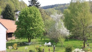 Un jardin avec une chaise et une table blanches, entouré de différentes plantes et arbres.
