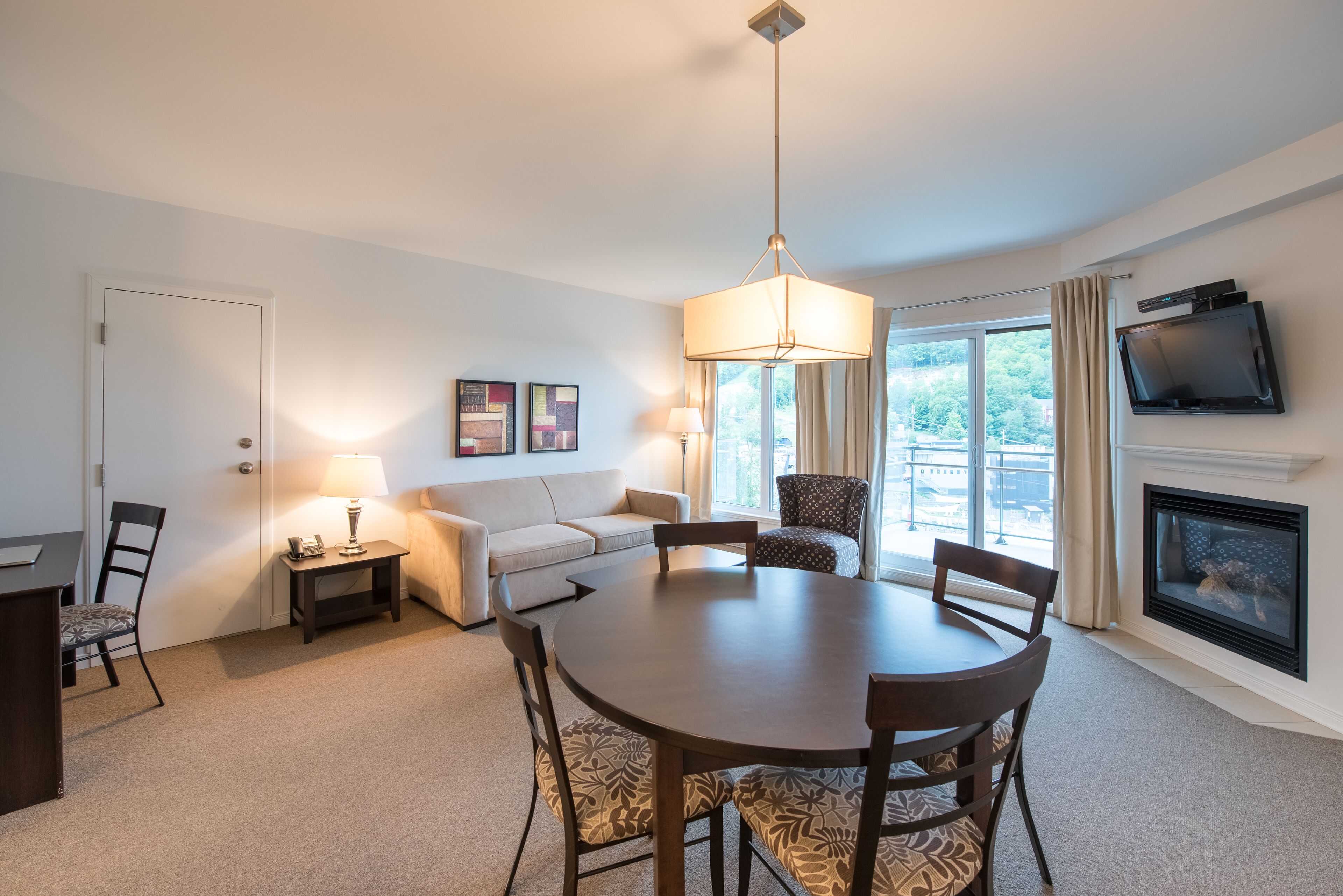 A modern living room with a round dining table, a sofa, a TV, and a fireplace.