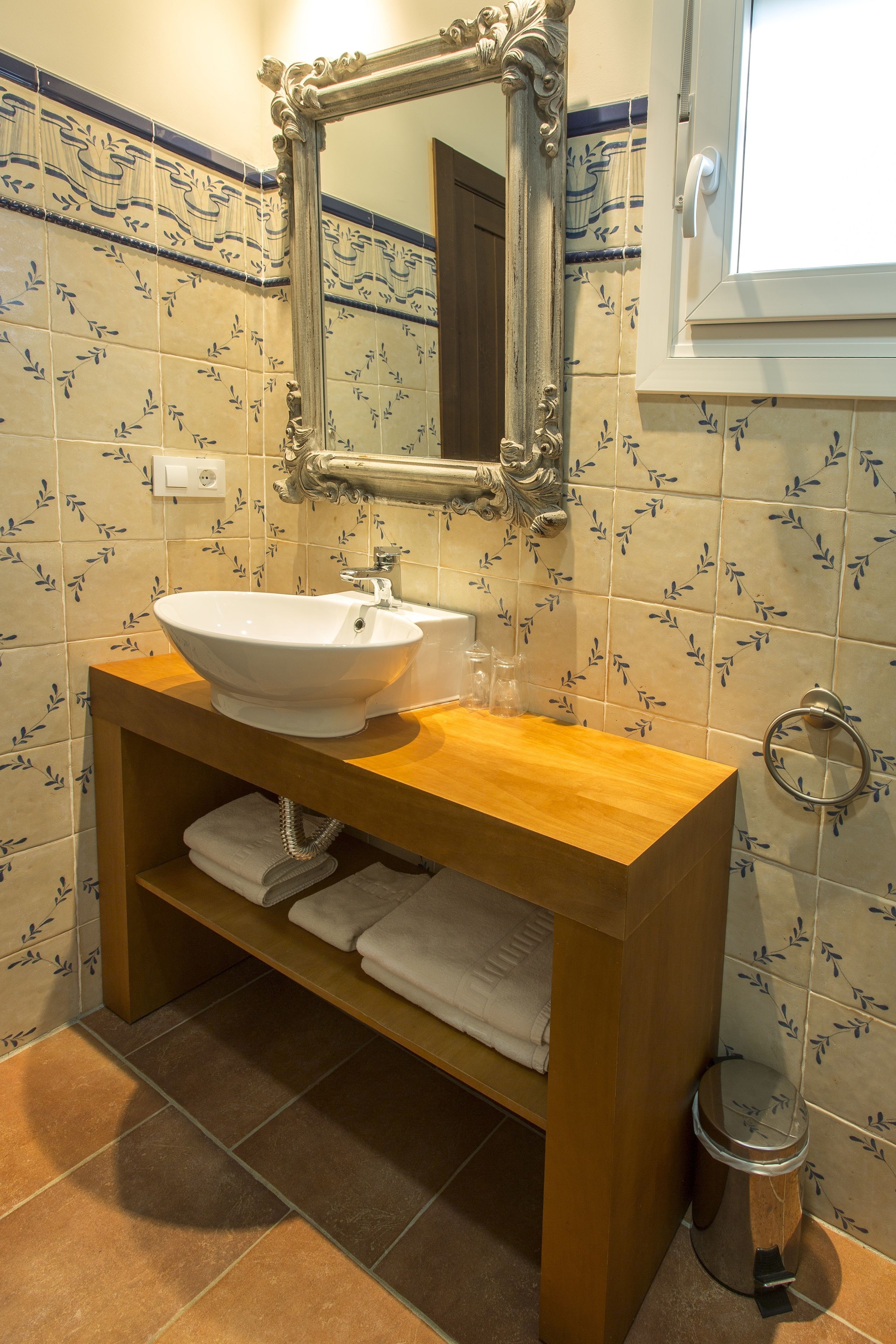 Un baño con tocador de madera, un lavabo blanco y un espejo.