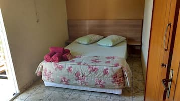 Un dormitorio con cama, ropa de cama floral, dos almohadas y cabecera de madera.
