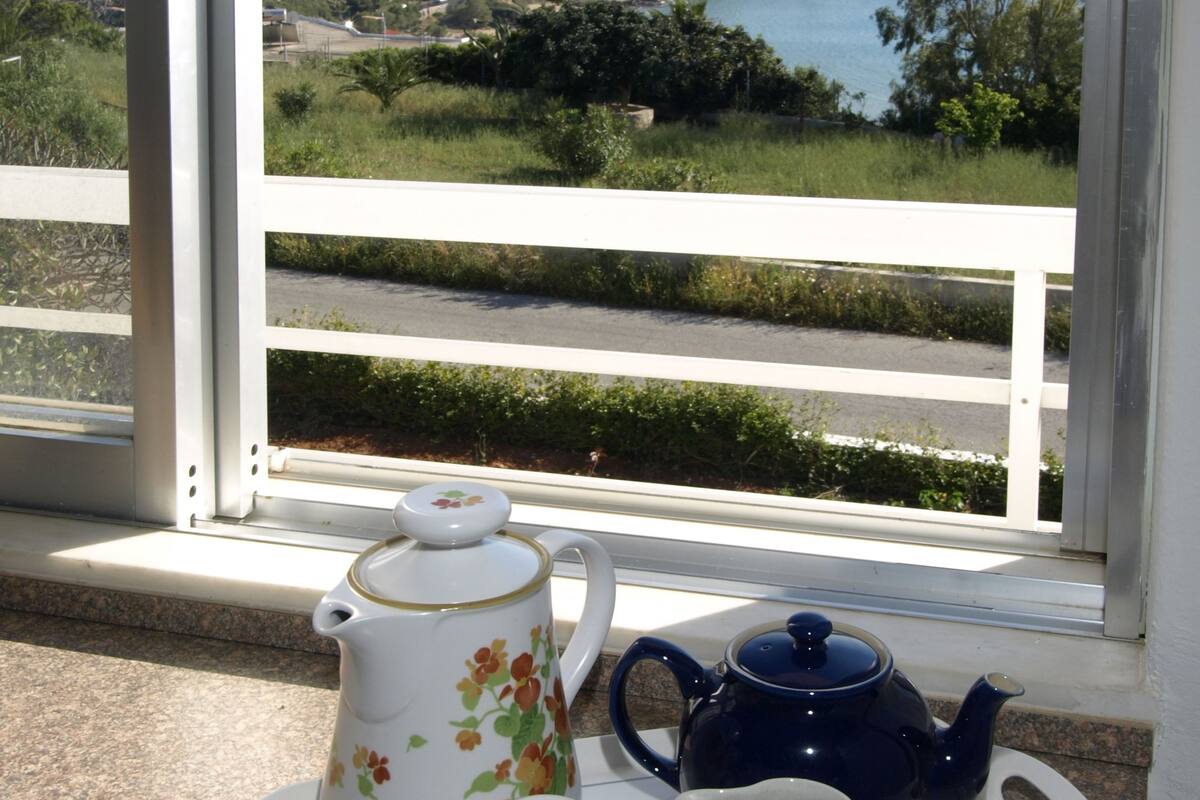 Una bandeja con tetera, tazas y azucarero en un balcón con vistas a un paisaje pintoresco.
