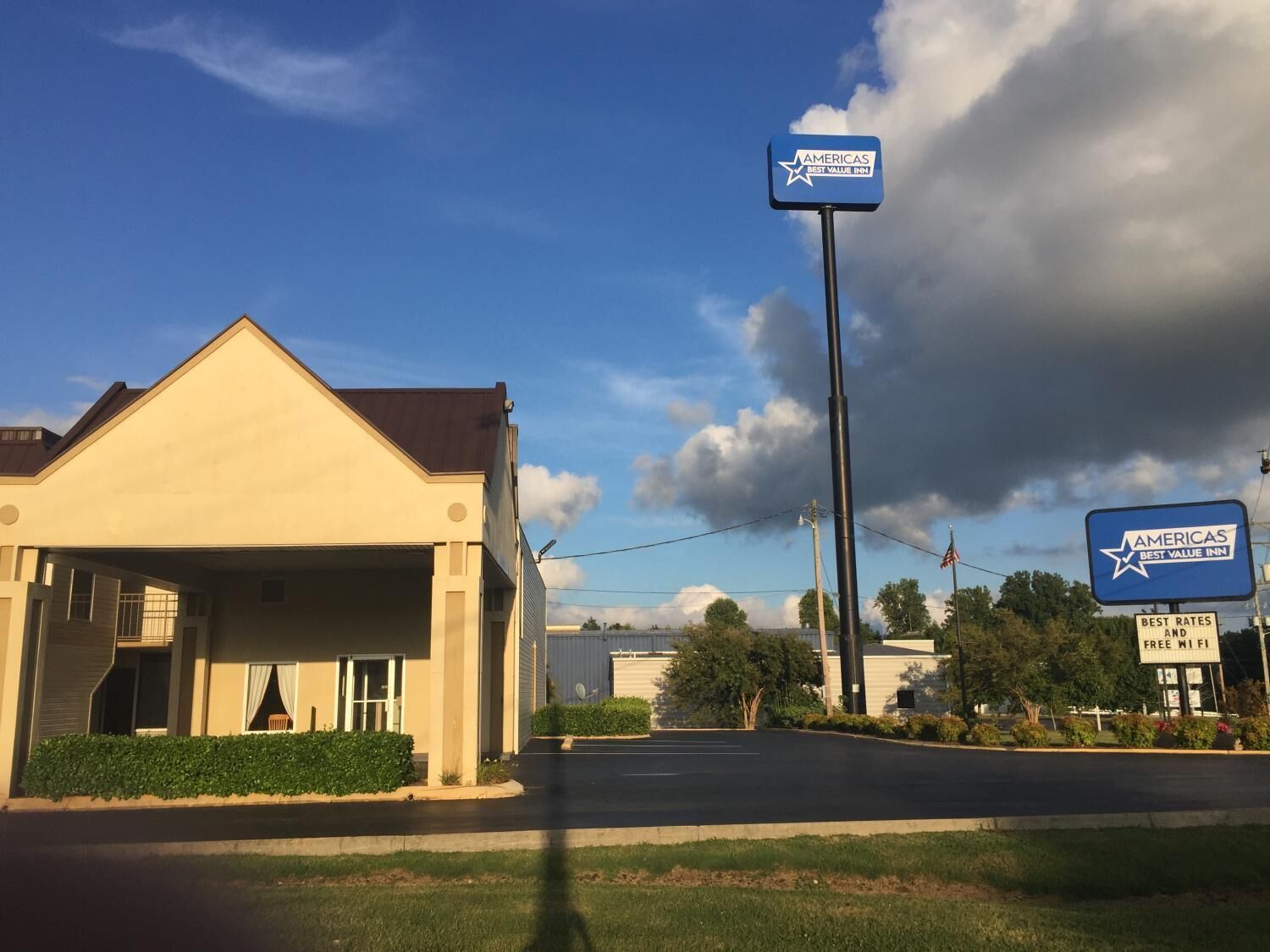 Un edificio con el cartel de Americas Best Value Inn, que cuenta con un estacionamiento y un cielo despejado.