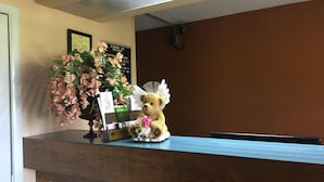 A reception desk with a teddy bear, a floral arrangement, and a welcome sign. - Americas Best Value Inn Manchester, TN (Manchester)
