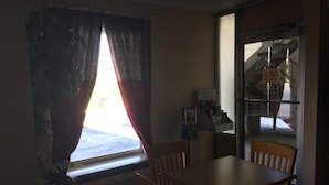 A dining area with a table and chairs, a window with curtains, and a view of a staircase and outdoor area. - Americas Best Value Inn Manchester, TN (Manchester)