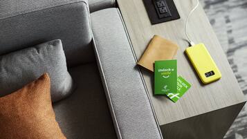 Una sala de estar moderna con un sofá gris, una mesa de centro de madera y un cargador portátil amarillo.