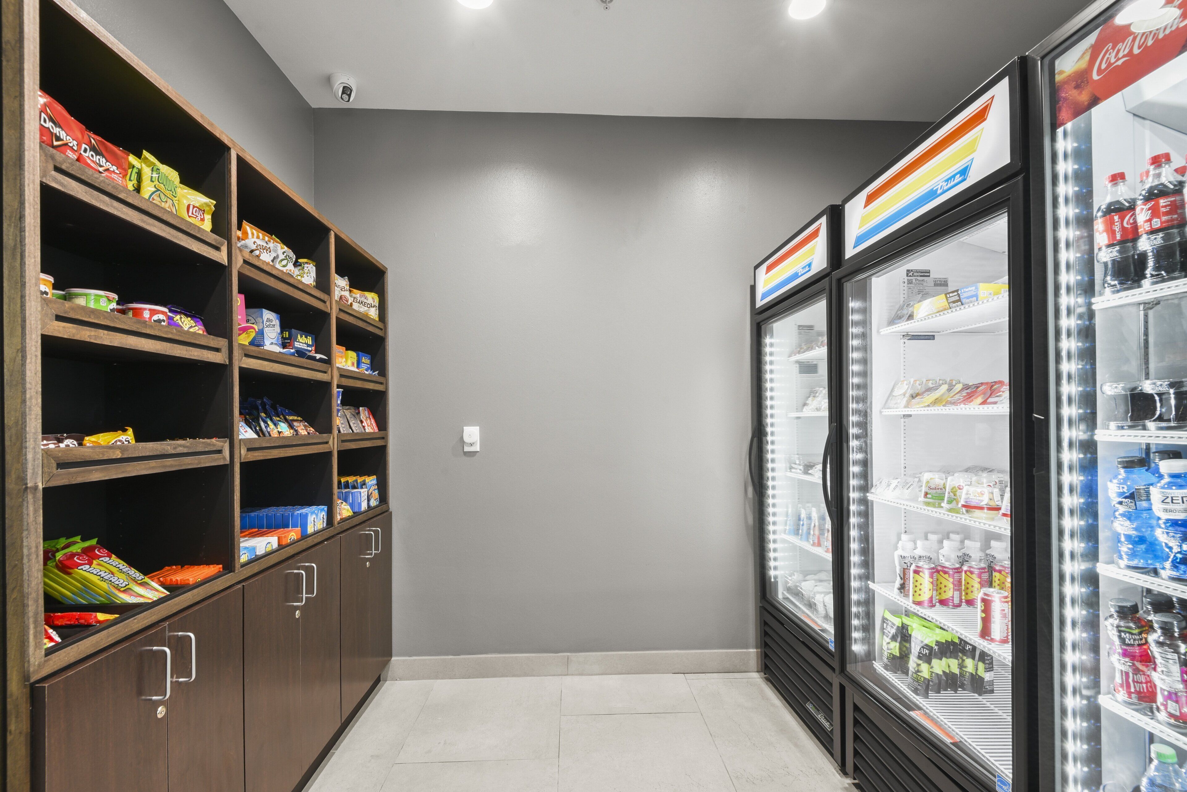 Ein Bereich mit Snacks und Getränken, mit Regalen voller verschiedener Snacks und einem Kühlschrank für abgefüllte Getränke.