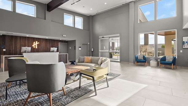 A spacious living area with a reception desk, seating arrangements, and large windows providing natural light. - Holiday Inn Gonzales by IHG (Gonzales)