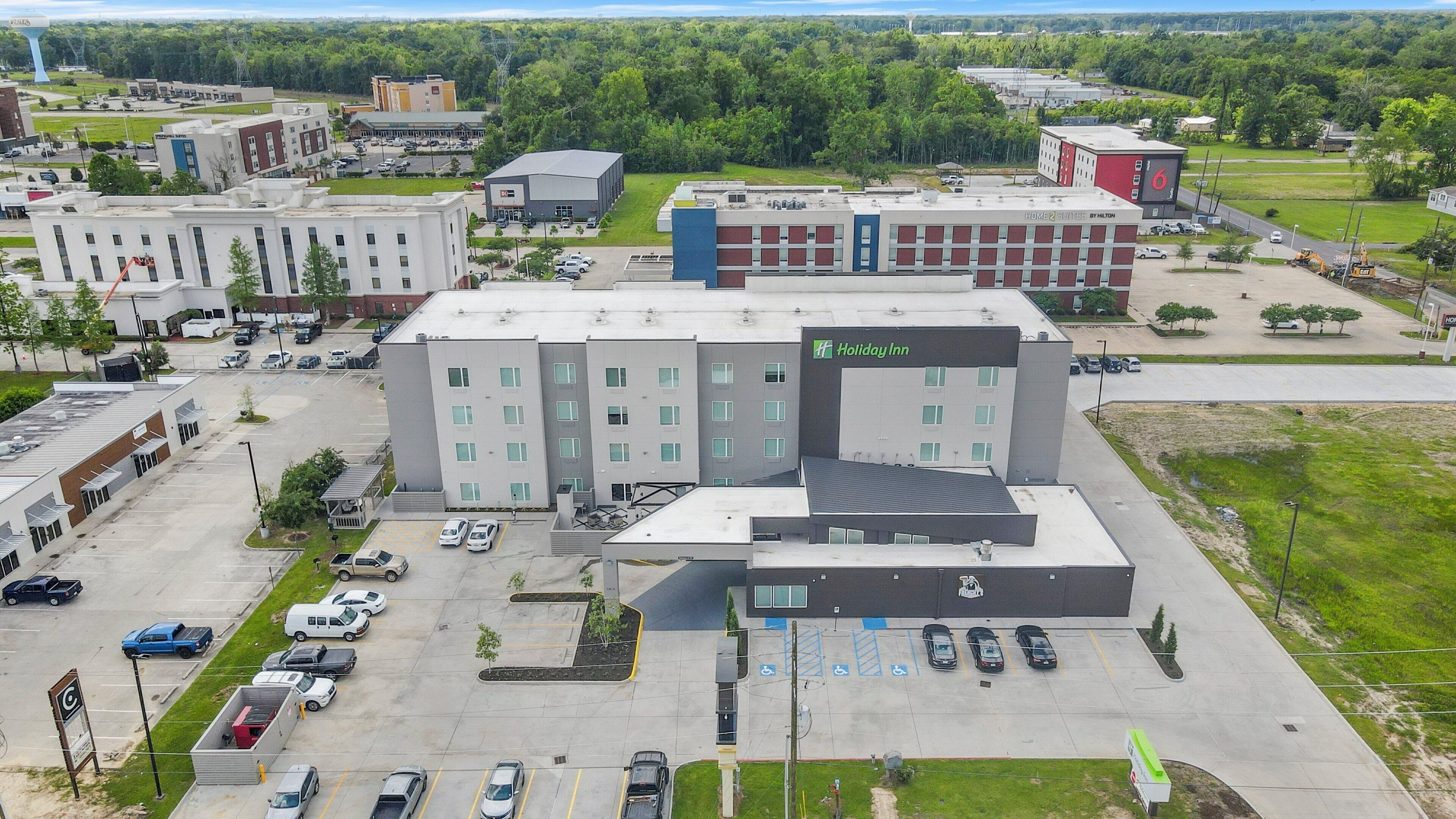 Un hôtel doté d’un grand parking, de plusieurs bâtiments et d’une enseigne Holiday Inn bien visible.