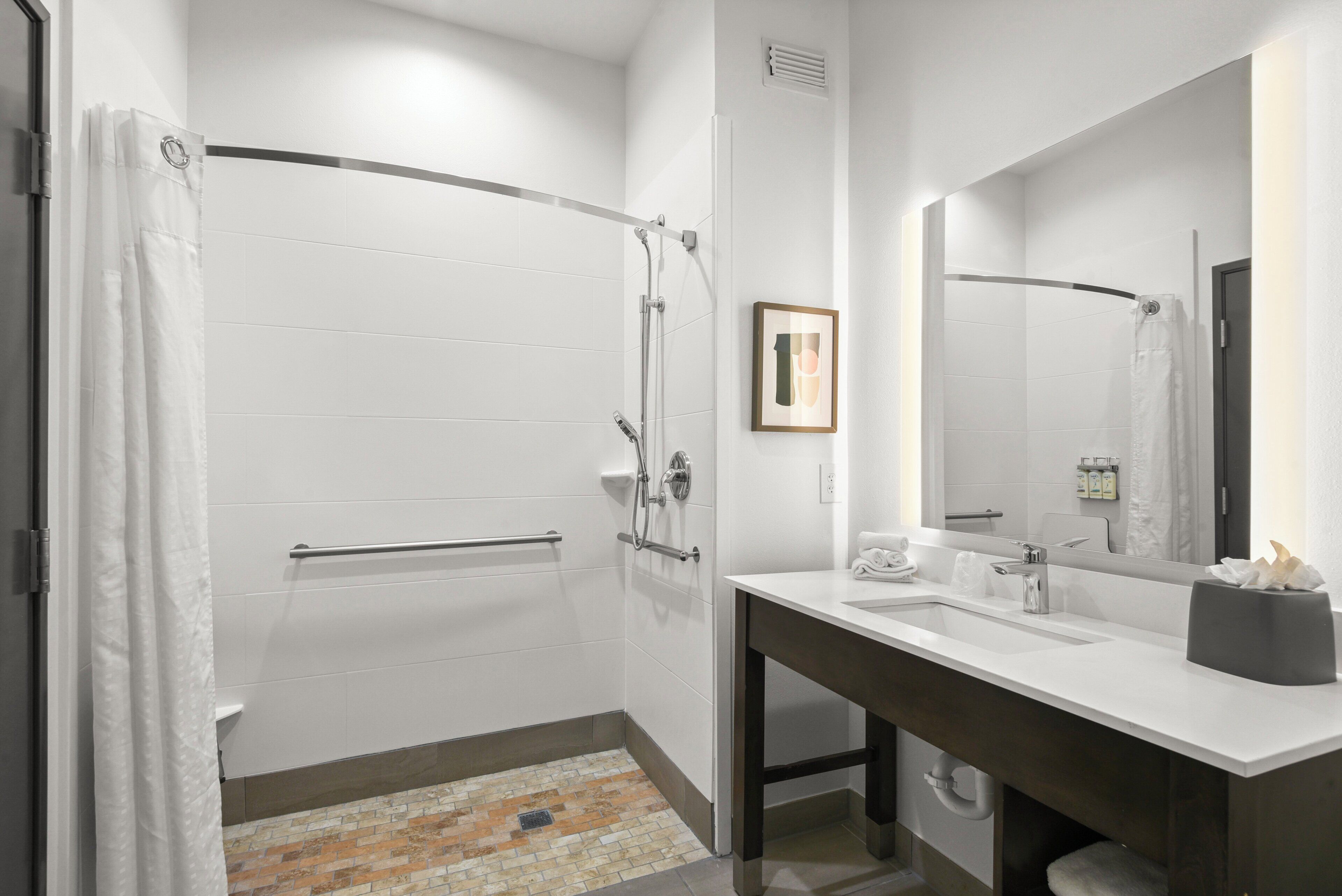 Een moderne badkamer met een douche, wastafel en spiegel.