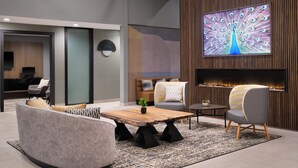 A modern living room with a large TV, comfortable seating, and a fireplace. - Holiday Inn Gonzales by IHG (Gonzales)
