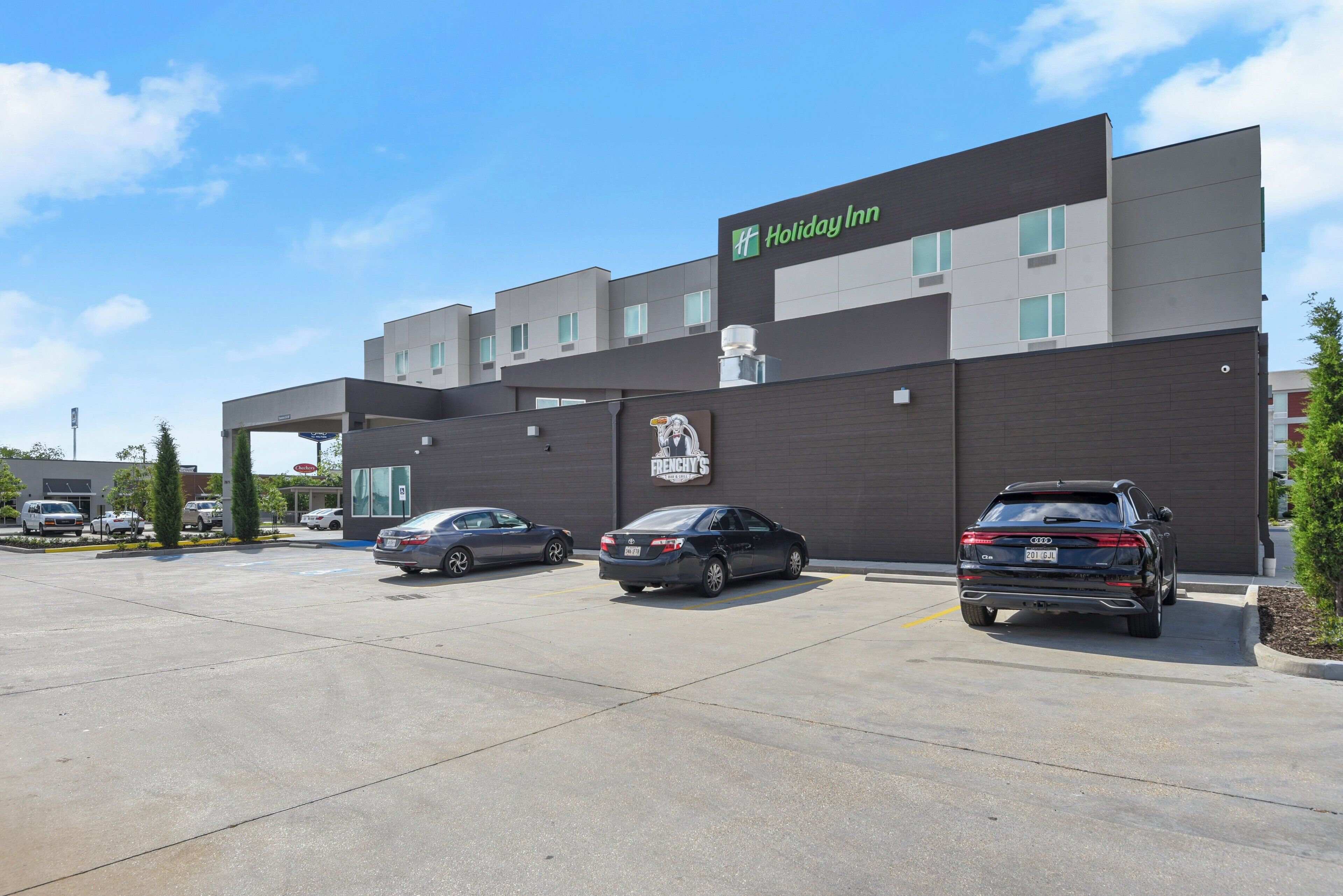 A Holiday Inn Express hotel with a parking lot and three cars parked in front.