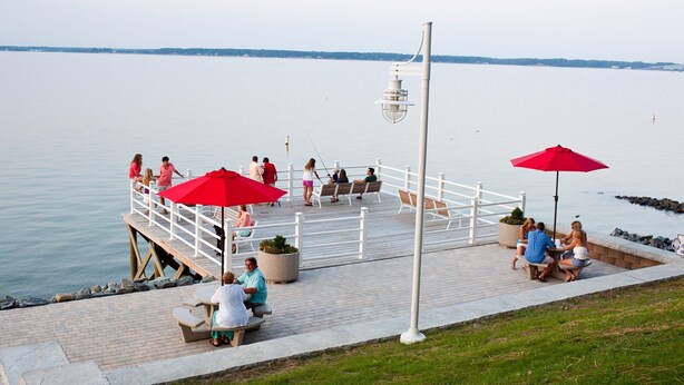 A waterfront deck with seating areas, a railing, and a view of the water. - Grey's Point Camp (Topping)