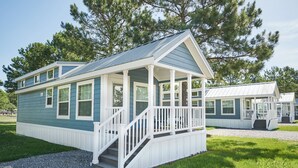 A small, single-story house with a porch and a covered front porch area. - Grey's Point Camp (Topping)