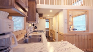 A modern kitchen with marble countertops, stainless steel appliances, and wooden cabinetry. - Grey's Point Camp (Topping)