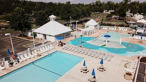 A large outdoor swimming pool with multiple lanes, surrounded by lounge chairs and umbrellas. - Grey's Point Camp (Topping)