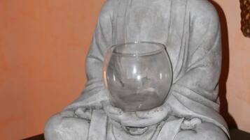 A statue of a seated figure holding a clear glass bowl.