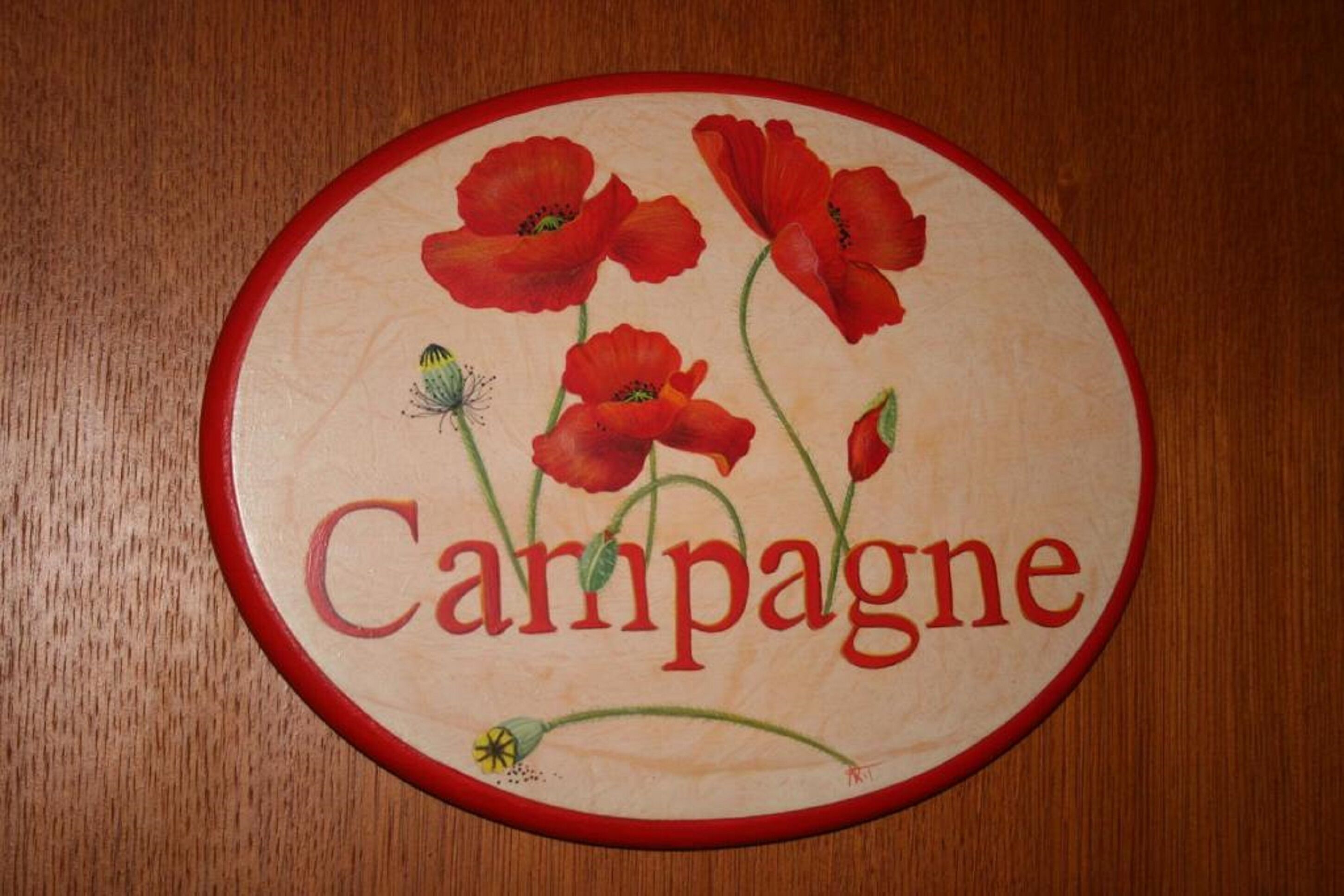 Un letrero circular con la palabra "Campagne" y flores de amapola rojas.