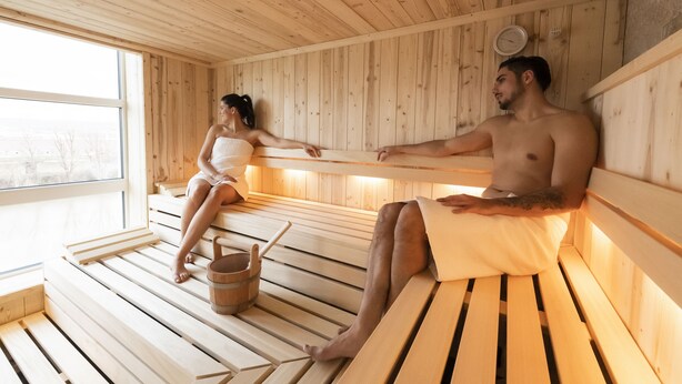 Una sauna con bancos de madera y un cubo de madera.