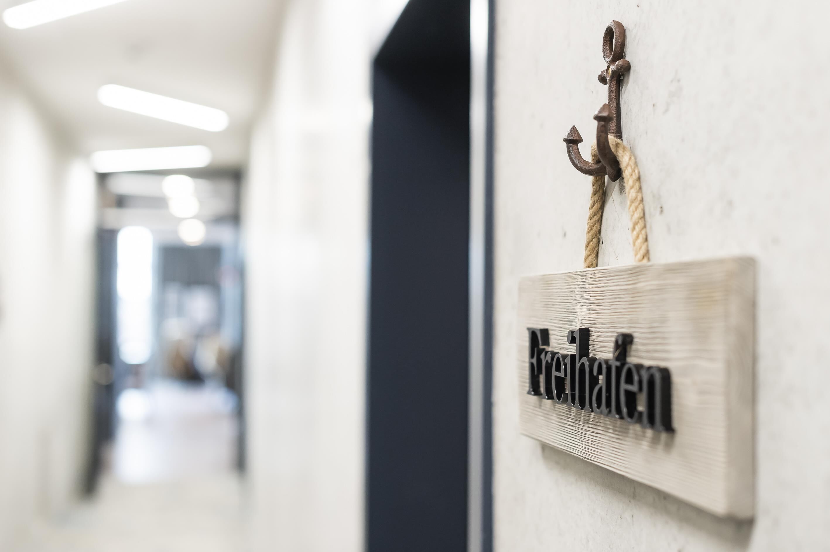 A hallway with a sign reading 'Fachzimmer' mounted on a wall with a rope and a metal hook.