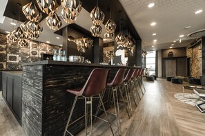 A modern bar area with a central island, bar stools, and pendant lighting. - HARBR. Hotel Heilbronn, a member of Radisson Individuals (Heilbronn)
