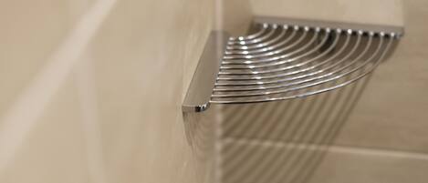 A metallic towel rack with a curved design, mounted on a beige tiled wall.