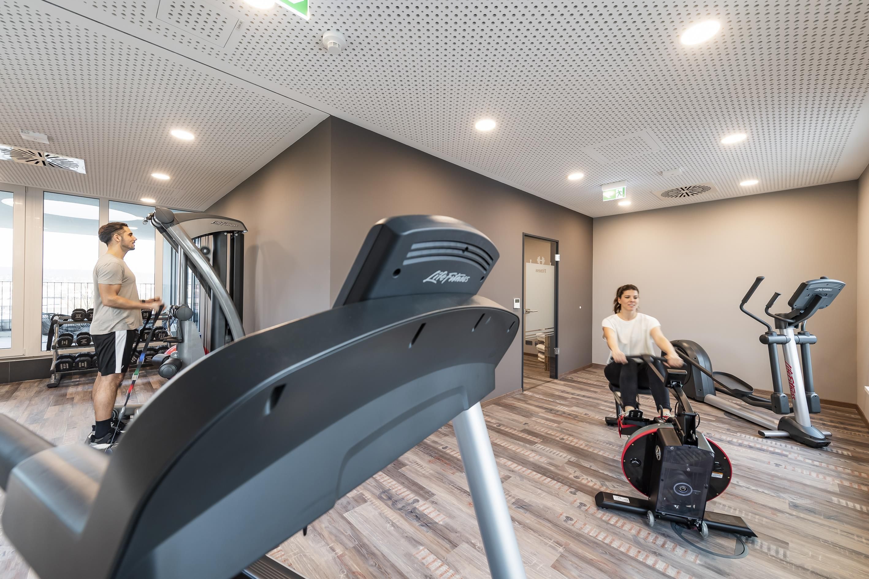 Ein Fitnessraum mit Laufbändern, Rudergeräten und Gewichten.