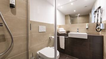 Un baño moderno con cabina de ducha de vidrio, inodoro, lavabo y toallero.