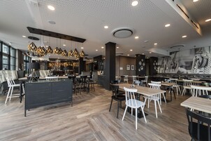 Un restaurante moderno con suelo de madera, sillas blancas y negras e iluminación colgante.