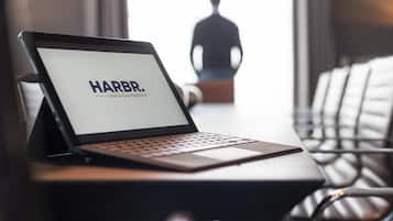 Un ordinateur portable est posé sur un bureau, et son écran affiche le texte « HARBR. hôtel et maison de tourisme ».